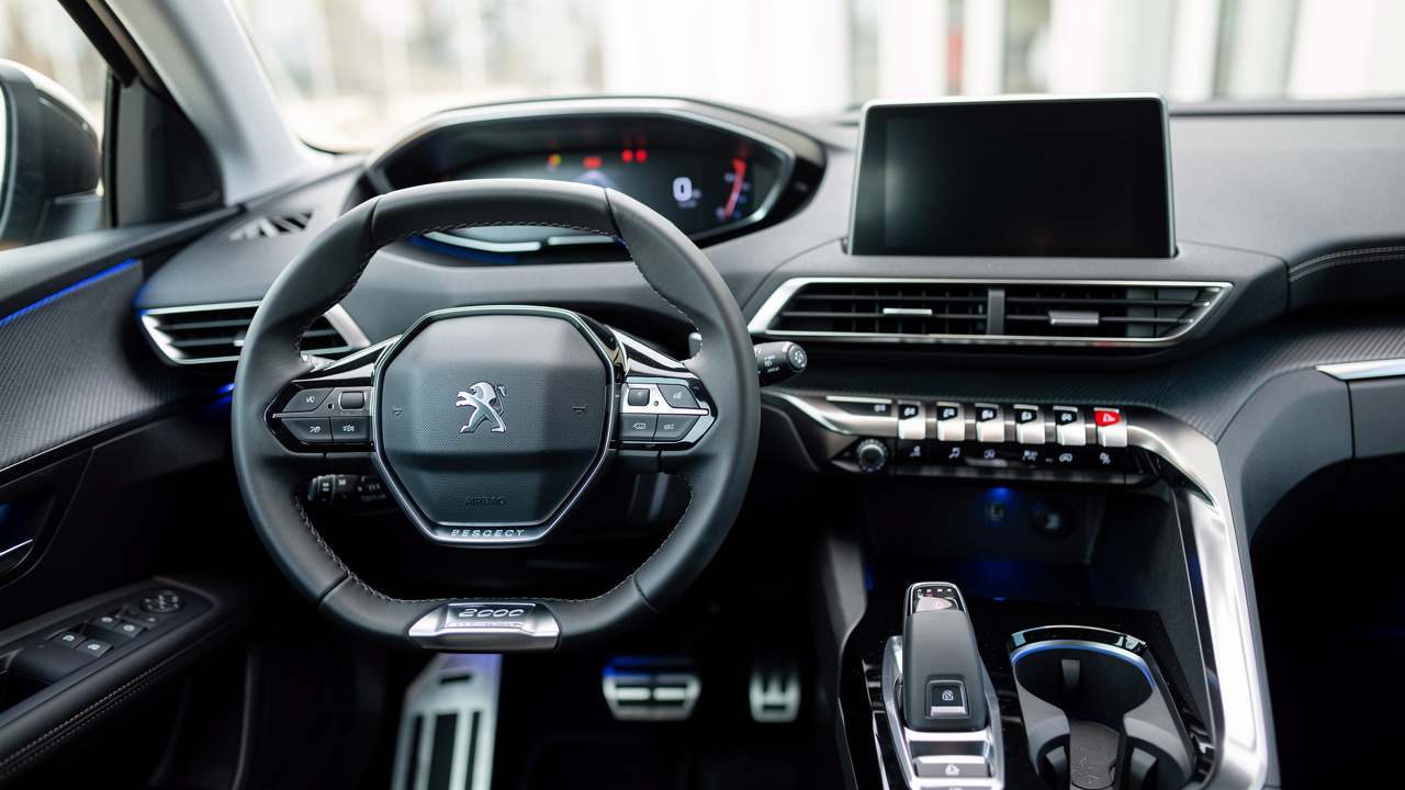 Intérieur d’une voiture Peugeot 3008 avec i-Cockpit, mise au point sur le volant compact et l’écran central, vue détaillée du tableau de bord sous un éclairage naturel.
