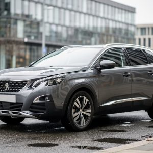 Vue trois quarts avant d’un Peugeot 3008 gris stationné en ville, ambiance de guide d’achat automobile, éclairage de journée doux et reflets réalistes sur la carrosserie.