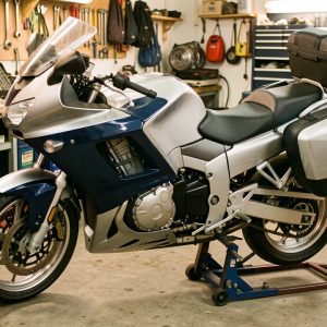 Moto de tourisme routière argentée et bleu foncé inspectée dans un atelier mécanique propre et organisé.