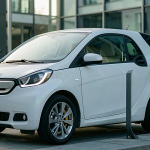 Voiture électrique moderne garée près d’une borne de recharge, avec un smartphone affichant une interface abstraite et épurée.
